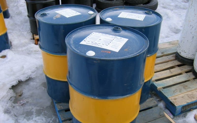 Fûts de carburant bleus et jaunes posés sur des palettes